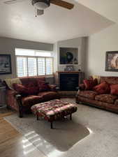 Living room featuring hardwood / wood-style flooring, ceiling fan, vaulted ceiling, and a textured ceiling