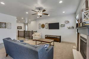 Living room featuring a tile fireplace and ceiling fan