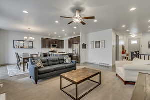 Living room featuring ceiling fan with notable chandelier and light hardwood / wood-style flooring