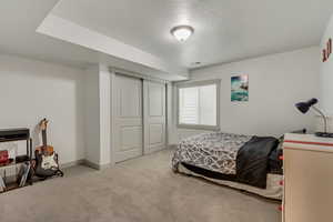 Bedroom with light colored carpet, a textured ceiling, and a closet