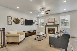 Living room featuring ceiling fan, a tile fireplace, and light wood-type flooring