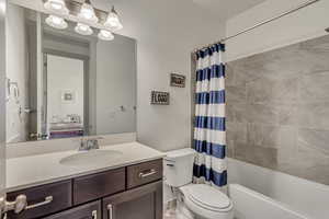 Full bathroom with vanity, shower / bath combination with curtain, and toilet