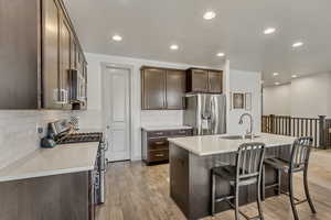 Kitchen with an island with sink, stainless steel appliances, sink, and light wood-type flooring