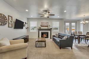 Living room featuring a healthy amount of sunlight, ceiling fan with notable chandelier, and light hardwood / wood-style flooring