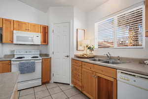 Kitchen featuring light tile patterned flooring, sink, and white appliances