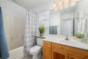 Full bathroom with tile patterned flooring, vanity, toilet, and shower / bath combo with shower curtain