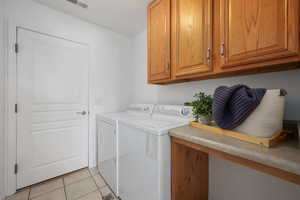 Laundry room featuring cabinets, light tile patterned floors, and independent washer and dryer