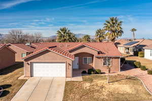 View of front of home with a garage, a mountain view, and a front lawn