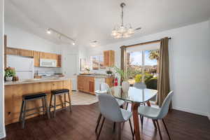 Dining area with vaulted ceiling, rail lighting, hardwood / wood-style floors, and a chandelier