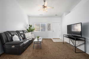 Carpeted living room with ceiling fan