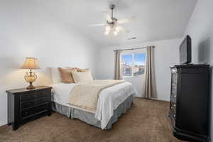 Bedroom with ceiling fan, vaulted ceiling, and dark colored carpet