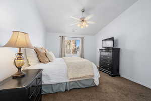 Carpeted bedroom featuring vaulted ceiling and ceiling fan