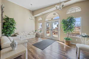 Living room featuring dark wood-type flooring, french doors, a chandelier, and a high ceiling