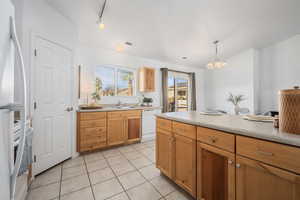 Kitchen with pendant lighting, sink, white appliances, light tile patterned floors, and rail lighting