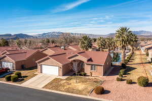 View of front of home with a garage, a mountain view, and a front lawn