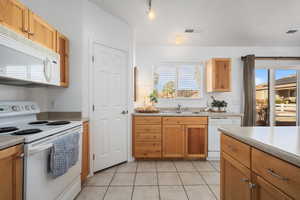 Kitchen featuring sink, white appliances, and light tile patterned flooring