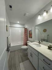 Full bathroom featuring shower / tub combo, vanity, a textured ceiling, and toilet