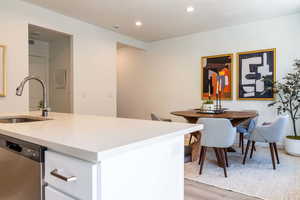 Kitchen with sink, stainless steel dishwasher, and light hardwood / wood-style floors