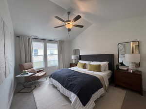 Carpeted bedroom featuring vaulted ceiling, ceiling fan, and a textured ceiling