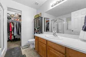 Bathroom with vanity, a shower with shower door, and toilet