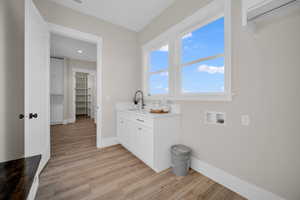 Laundry room featuring cabinets, sink, washer hookup, and light hardwood / wood-style floors