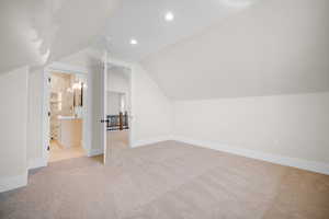 Bonus room with light colored carpet, sink, and vaulted ceiling