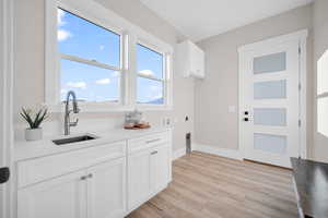 Kitchen with sink, white cabinets, and light wood-type flooring