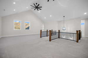 Interior space featuring plenty of natural light, ceiling fan with notable chandelier, light carpet, and high vaulted ceiling