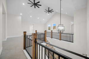 Hall featuring vaulted ceiling, light colored carpet, and a notable chandelier