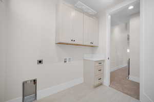 Clothes washing area with washer hookup, cabinets, light colored carpet, and hookup for an electric dryer