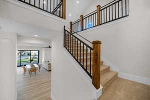 Stairway with hardwood / wood-style flooring and a towering ceiling