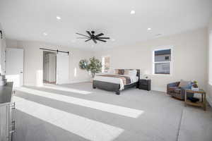 Carpeted bedroom with ceiling fan and a barn door