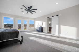 Bedroom with ceiling fan, french doors, access to outside, light colored carpet, and a barn door