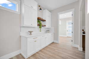 Kitchen featuring white cabinetry, tasteful backsplash, and light wood-type flooring