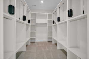 Spacious closet featuring light colored carpet