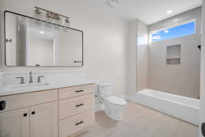 Full bathroom with tiled shower / bath combo, vanity, and toilet