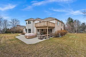 Rear view of house featuring a yard, a hot tub, a deck, and a patio