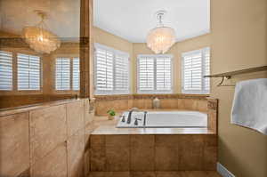 Bathroom with an inviting chandelier and tiled tub