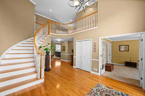 Foyer entrance featuring hardwood / wood-style flooring, a notable chandelier, ornamental molding, and a high ceiling