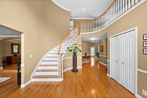 Entrance foyer with hardwood / wood-style flooring, crown molding, and a towering ceiling