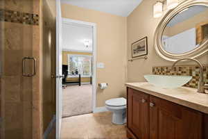 Bathroom featuring vanity, decorative backsplash, a shower with shower door, tile patterned floors, and toilet