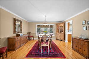 Dining area with crown molding, a textured ceiling, and light wood-type flooring