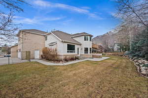 Rear view of house with a patio, a mountain view, a lawn, and a jacuzzi