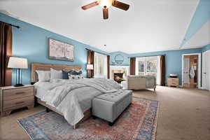 Bedroom featuring ceiling fan, lofted ceiling, carpet, and a tile fireplace