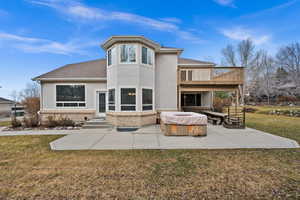 Back of property with a patio area, a hot tub, and a lawn