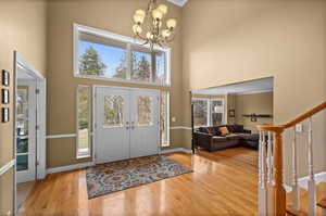 Entrance foyer with hardwood / wood-style flooring, a chandelier, and a high ceiling