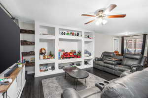 Living room featuring dark hardwood / wood-style floors, built in features, and ceiling fan