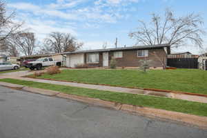 Ranch-style home with a garage and a front yard - enhanced grass