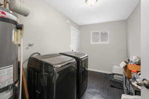 Clothes washing area with gas water heater, dark hardwood / wood-style floors, and washer and clothes dryer