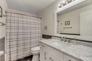 Bathroom featuring vanity, curtained shower, and toilet